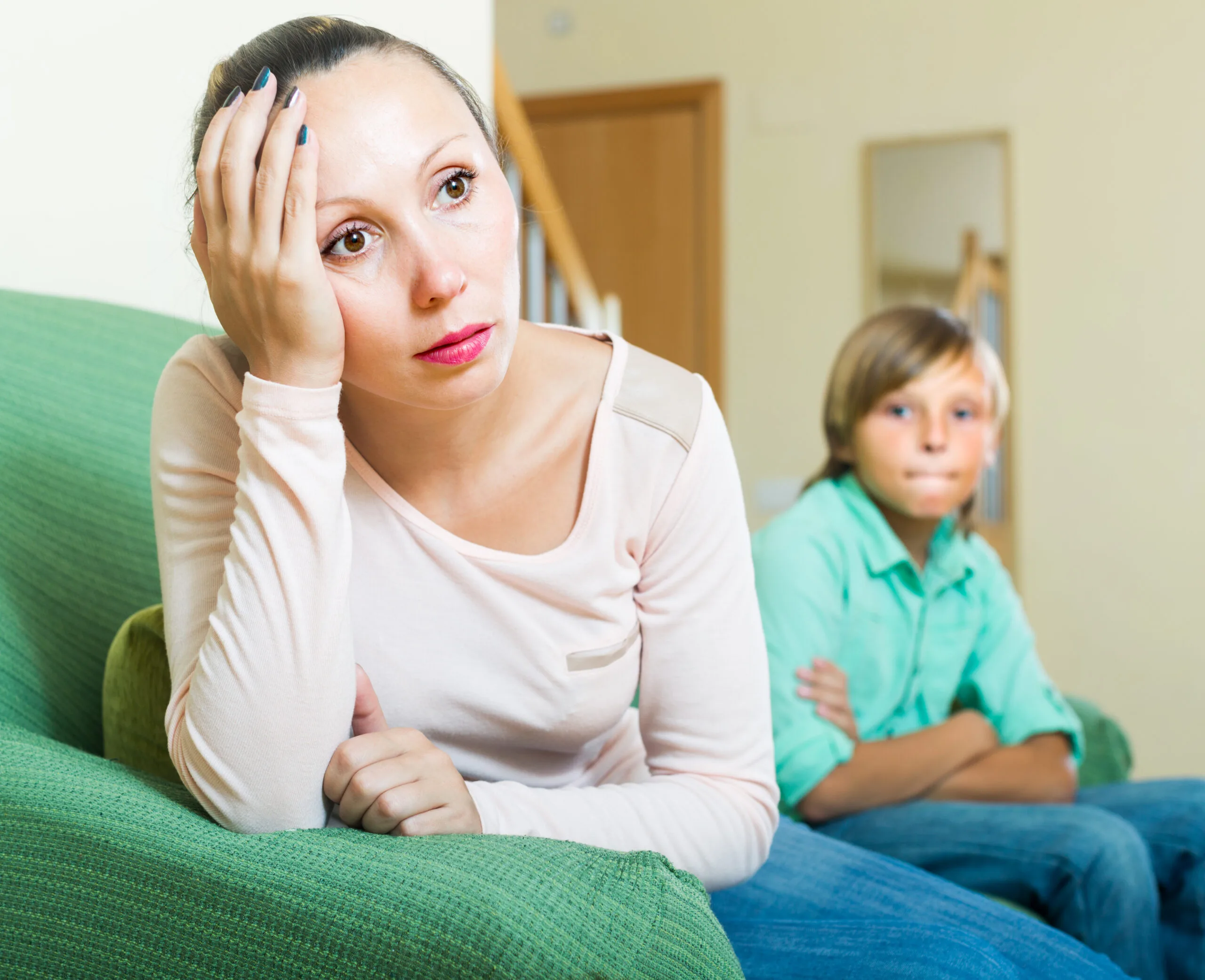 Mature mother sitting sad after conflict with teenager son at home