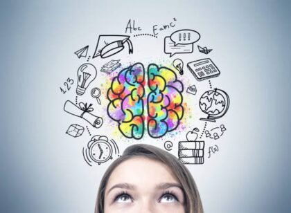 Close up of a blonde woman s head. She is standing near a gray wall and looking upwards. An education drawing and a brain sketch on the wall.