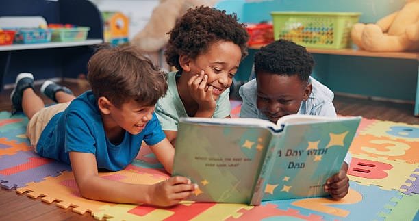 Boys, reading and friends on carpet, school and learning with education, relax and bonding together. Group, storytelling and children in classroom, literacy knowledge and happiness with break