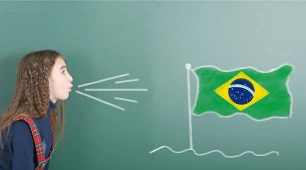 Pre-adolescent girl blowing on the school board drawn on the blackboard Brazil flag. High resolution photo. Full depth of field.