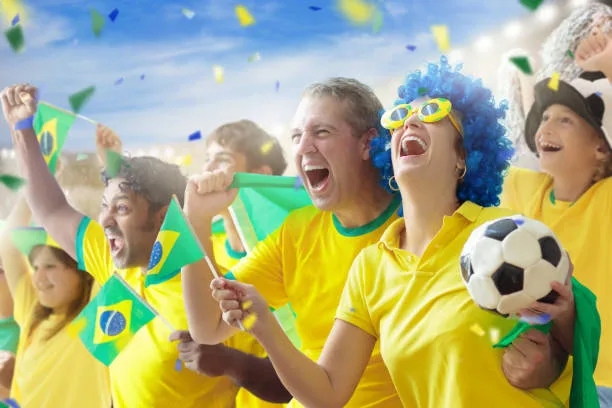 Brazil football supporter on stadium. Brazilian fans on soccer pitch watching team play. Group of supporters with flag and national jersey cheering for Brazil. Championship game.